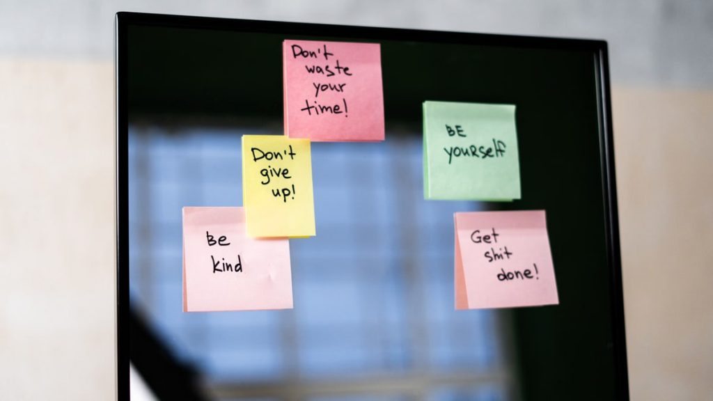 Colorful sticky notes on a mirror provide daily motivational messages and positivity reminders.